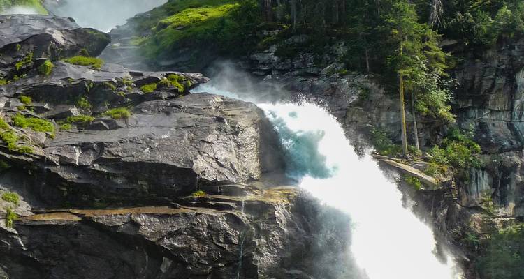 Gros plan d'une cascade tumultueuse entourée de verdure.