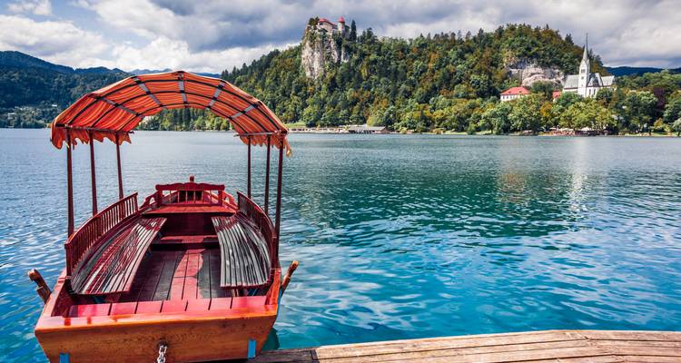 Barco tradicional de madera en el Lago Bled con la iglesia en una colina.