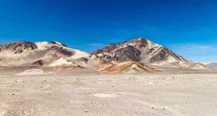 Paisaje desértico con montañas áridas bajo un cielo azul despejado.