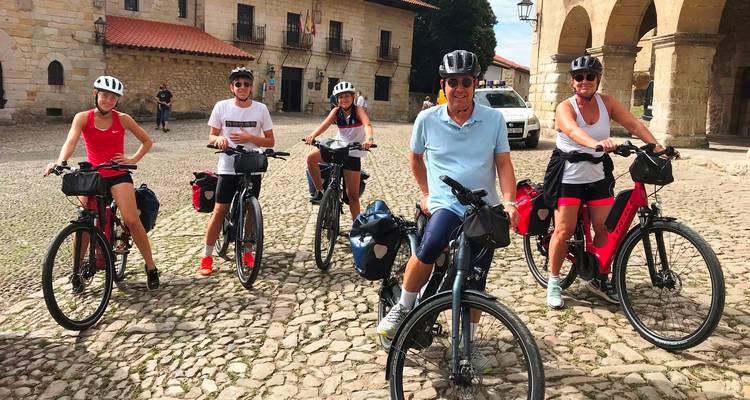 Groupe de cyclistes debout sur des pavés devant des bâtiments historiques.