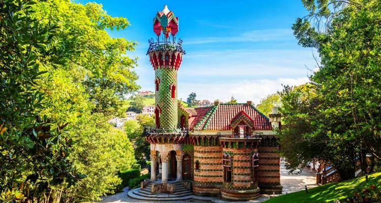 El Capricho de Gaudí, un bâtiment coloré et orné entouré d'un jardin verdoyant luxuriant.