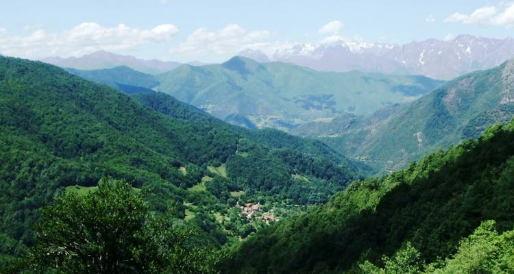 Des vallées verdoyantes luxuriantes avec des montagnes lointaines sous un ciel dégagé.