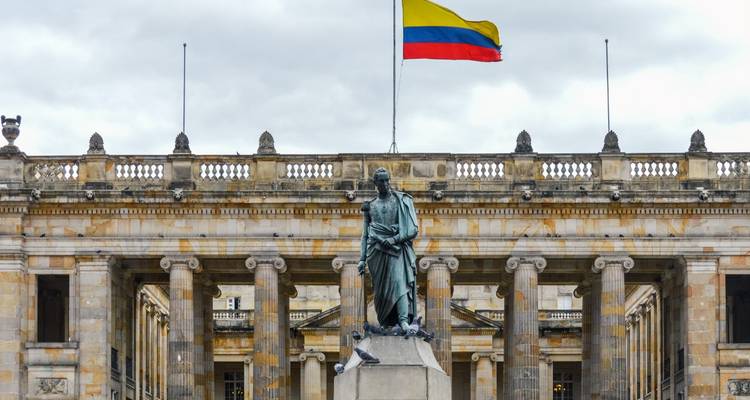 Statue vor einem prächtigen Gebäude mit der kolumbianischen Flagge.