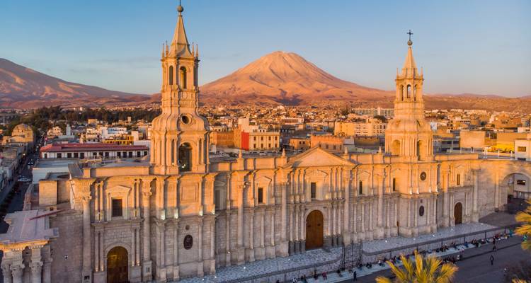 Luftaufnahme einer großartigen Kathedrale mit zwei Türmen und entfernter Bergkulisse während der goldenen Stunde.