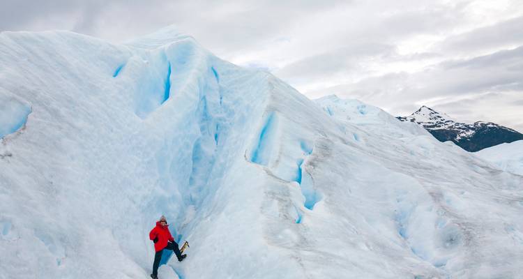 Persona escalando un gran glaciar con equipo.