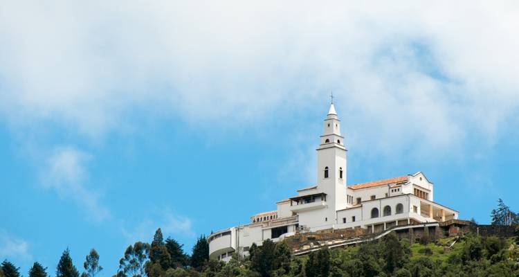 Église blanche sur une colline avec des nuages dans le ciel.