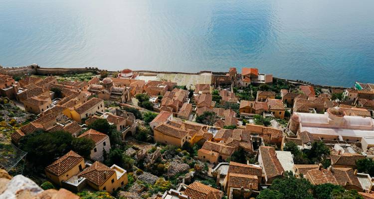 Luftaufnahme einer Küstenstadt mit traditioneller griechischer Architektur.