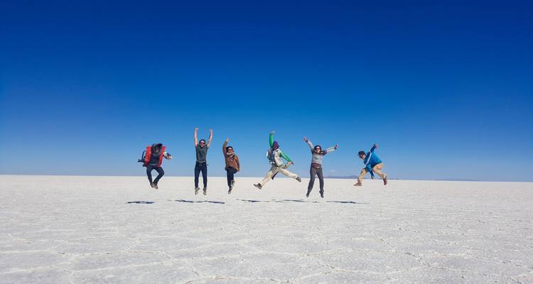 Grupo de personas saltando alegremente en las salinas con cielos azules despejados.
