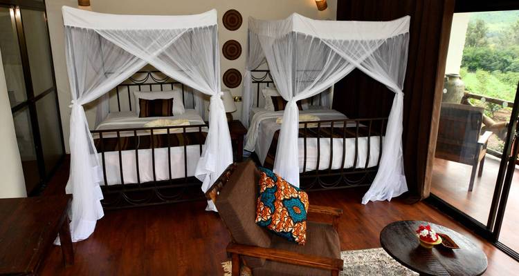 Intérieur d'une chambre avec deux lits à baldaquin et vue sur balcon.