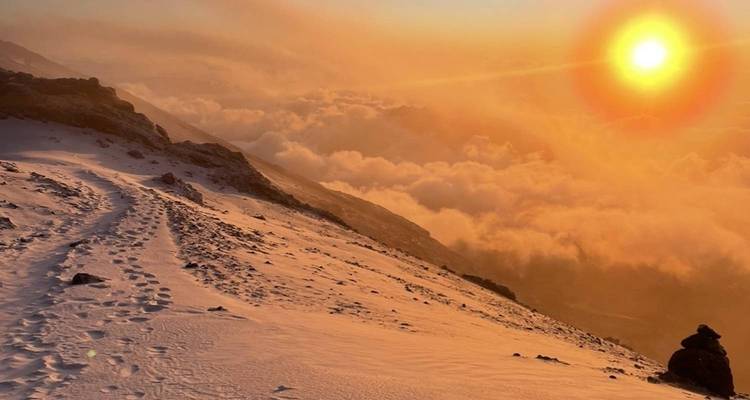 Coucher de soleil sur un sentier de montagne enneigé.