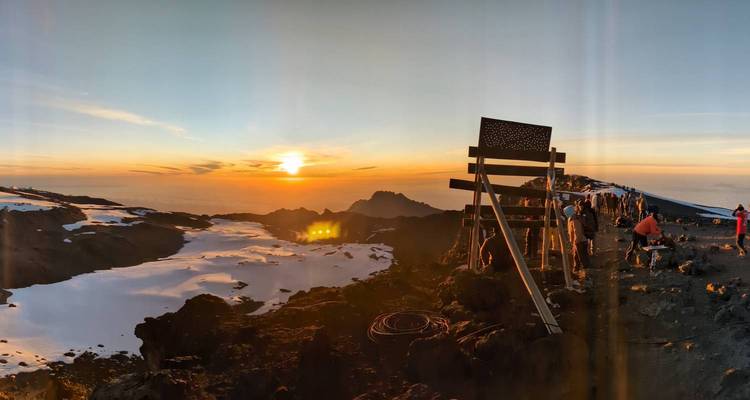 Vue du lever du soleil avec de la neige et une montagne au loin.