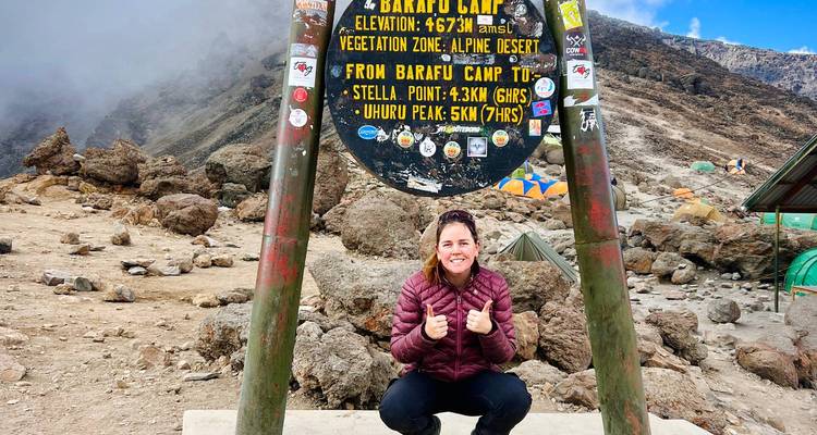 Femme posant au camp de Barafu avec un paysage montagneux.