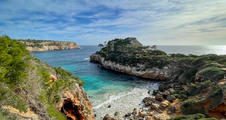 Un paysage côtier époustouflant avec des falaises, une mer turquoise et une petite plage en contrebas.