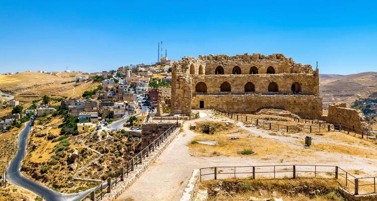 Panoramablick auf die Ruinen der Burg Kerak, die die Hügelstadt unter klarem blauem Himmel dominieren.
