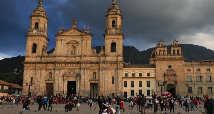 Des foules se rassemblent devant une grande cathédrale par un après-midi dramatiquement nuageux.