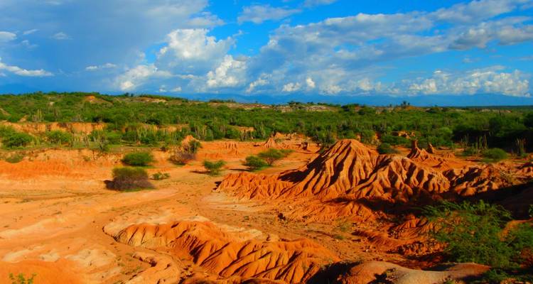 Crêtes orange vives et ravins secs du désert de Tatacoa en Colombie sous des nuages épars.