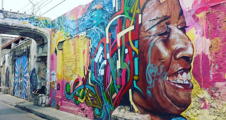 Murale d'art urbain colorée représentant un visage souriant sur un mur patiné à Cartagena.