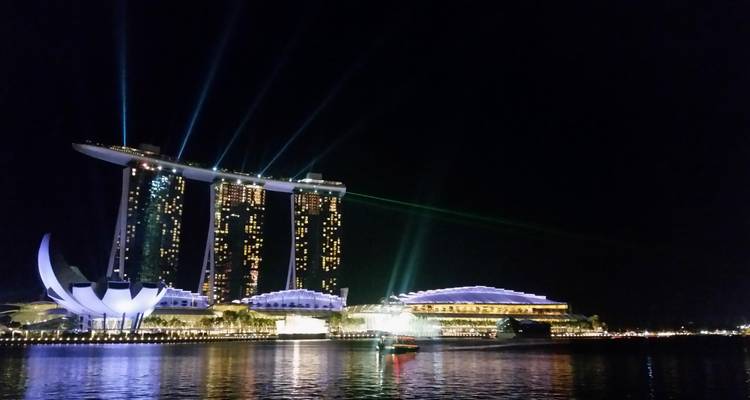 Hôtel emblématique Marina Bay Sands et Musée ArtScience illuminés la nuit avec des faisceaux laser au-dessus de l'eau.