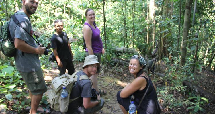 Petit groupe de randonneurs fait une pause sur un sentier de jungle entouré d'une végétation verte dense.