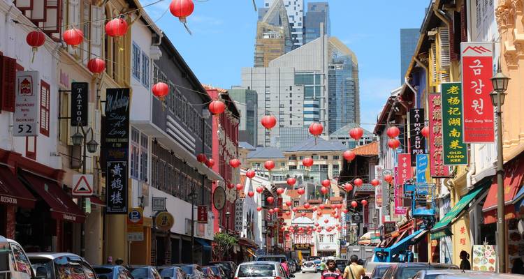 Rue vibrante de Chinatown bordée de lanternes, de maisons-boutiques et de gratte-ciel qui se dressent en arrière-plan.