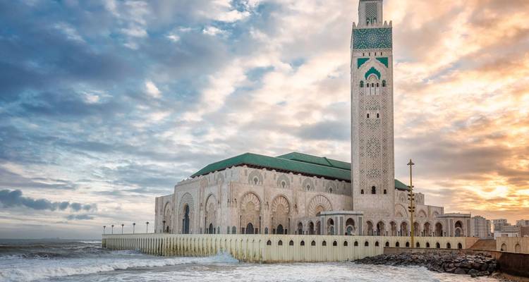 Majestueuse mosquée Hassan II au bord de l'océan Atlantique sous des nuages dramatiques de lever de soleil.