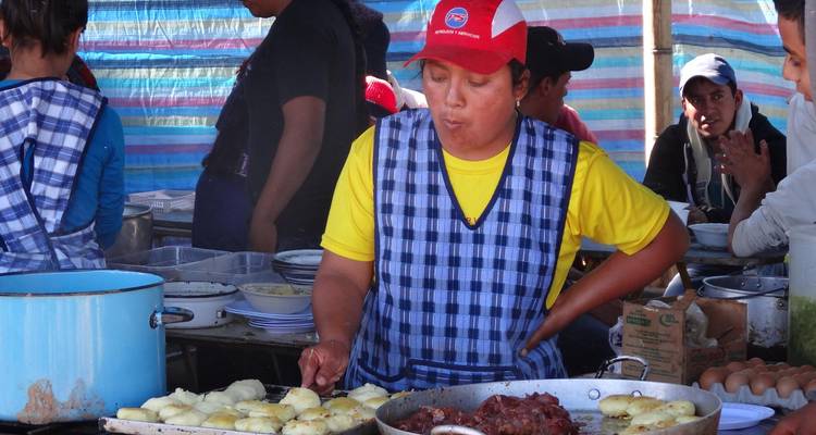 Straatvoedselkok in een geruite schort bereidt sissende gerechten bij een kraam op de openluchtmarkt.
