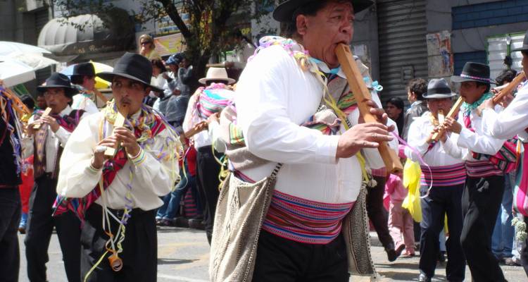 Straatparade van muzikanten in kleurrijke Andeskleding bespelen houten fluiten en marcheren door feestelijke menigten.