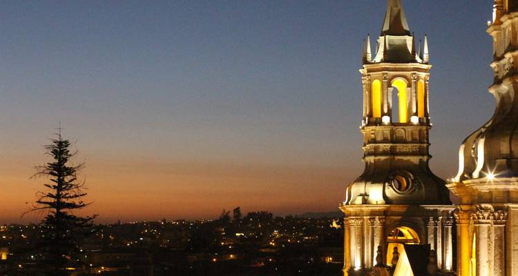Verlichte kathedraal torens rijzen op boven Arequipa's avondlucht met een warme gradiënt zonsondergang.