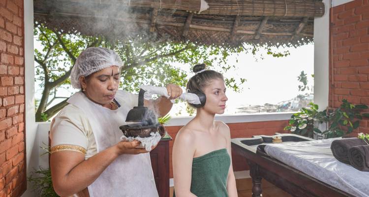 Een vrouw die een traditionele hoofdmassage krijgt in de buitenlucht.