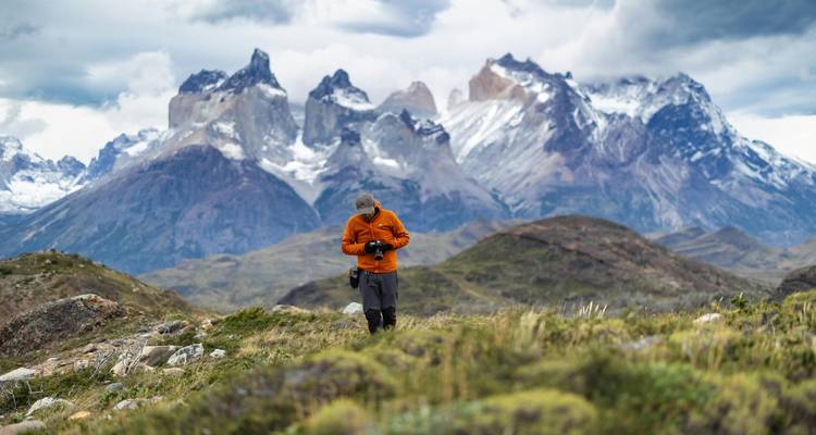 Wandelaar in oranje jas in een bergachtig landschap.