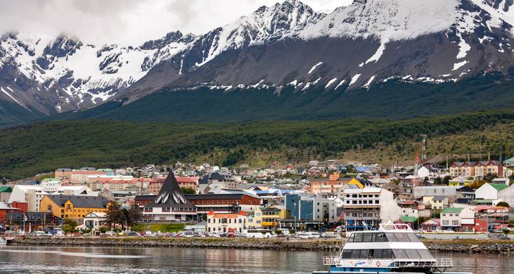 Paysage urbain avec des bâtiments colorés et des montagnes enneigées en arrière-plan.
