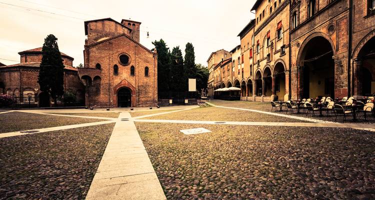 Historisch plein met kasseienbestrating en gebouwen met bogen.