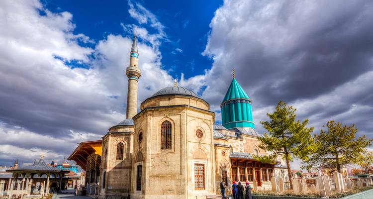 Mevlana-Museumskomplex in Konya mit türkisfarbener Kuppel und dramatischem wolkenverhangenem Himmel.