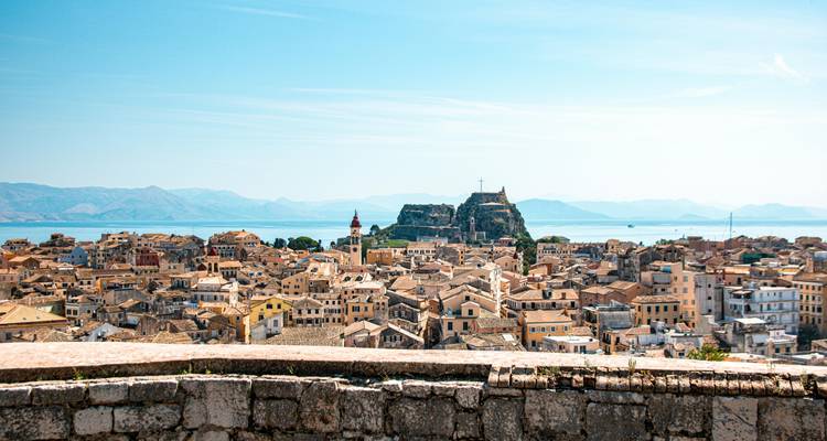 Vista panorámica de los tejados de terracota del Casco Antiguo de Corfú con la Fortaleza Vieja elevándose sobre el azul mar Jónico.