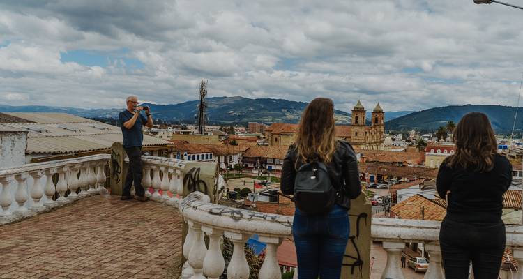 Menschen stehen auf einem Balkon mit Blick auf eine Stadt.