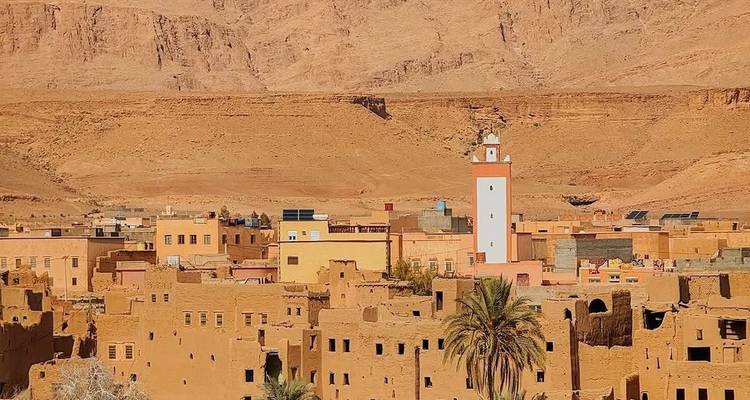 Wüstenlandschaft mit traditionellen Lehmziegelgebäuden unter klarem Himmel.