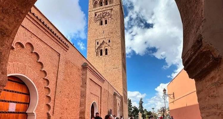 Komplizierter Moscheenturm und umliegende Architektur durch einen Torbogen betrachtet.