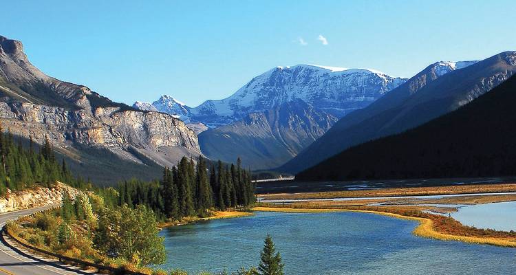 Route panoramique serpentant le long d'eaux turquoise et de sommets enneigés sur la Promenade des Glaciers.