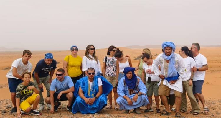 Groupe de personnes posant dans une zone désertique, certaines portant des tenues traditionnelles.