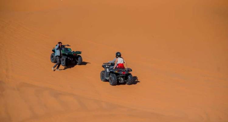 Dos personas en vehículos todo terreno en un paisaje desértico.