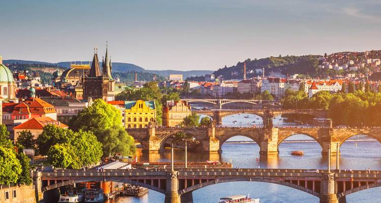 Vista aérea del río Moldava con puentes históricos y edificios de Praga bajo la luz del sol.
