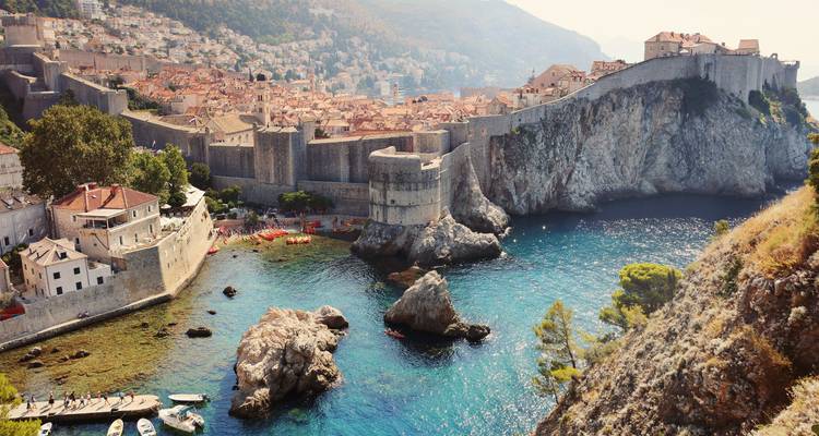 Forteresse historique et côte rocheuse avec mer bleue claire.