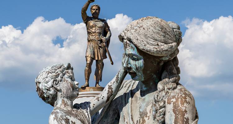 Gros plan de sculptures antiques qui se détériorent, l'une représentant un guerrier et l'autre une mère et son enfant.