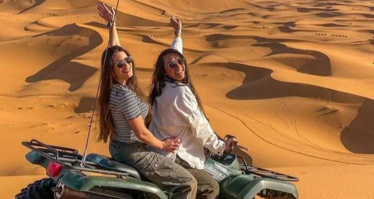 Zwei Frauen auf einem Quad, die die Sanddünen genießen.