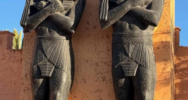 Zwei schwarze Statuen im ägyptischen Stil am Eingang eines Gebäudes.