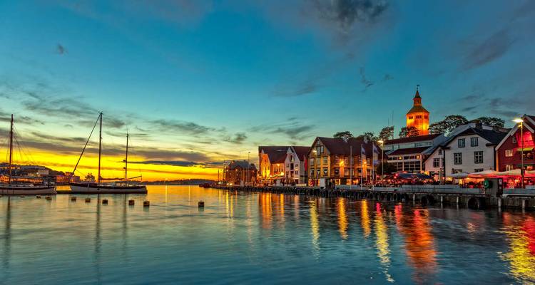 Vista del puerto al atardecer con edificios coloridos y barcos.