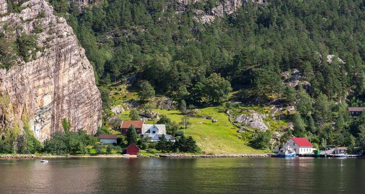 Paisaje rural con casas junto a un fiordo y bosque.