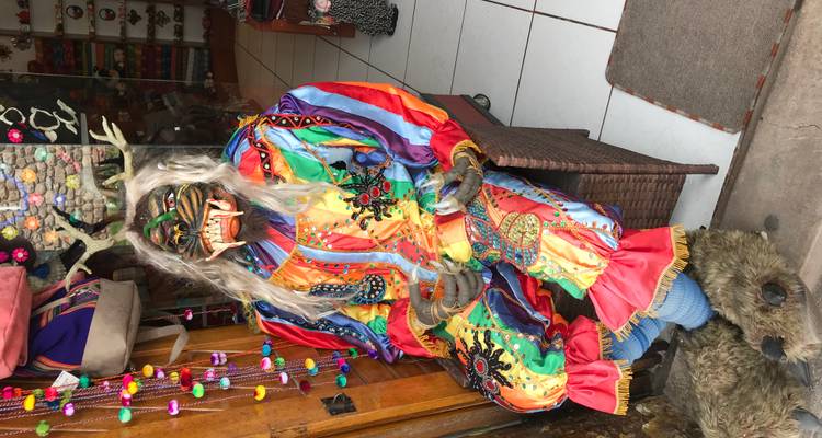 Un masque coloré et un costume exposés devant une boutique.