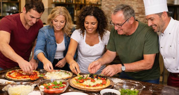 Groupe de personnes préparant une pizza ensemble.