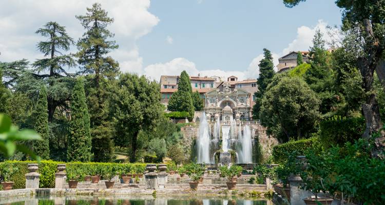 Jardins avec fontaines et arbres sous un ciel dégagé.
